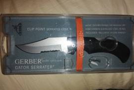 Gerber 06079 Folding Clip Point Serrated Gator Kni, Beand new. Still in box. Valued at R6375. Gator - Clip Point, Serrated 6079. The Gator folding knives feature surgical stainless steel blades and patented handles that set them apart from the competition. Gerber revolutionized knife grip technology when it introduced the Gator in 1991, winning Blade Magazine's Most Innovative Knife of the Year award. The Gator folders have handles made of a hard inner core of glass filled polypropylene, with Santoprene rubber molded and chemically bonded around it, essentially combining the two materials into one piece. This creates a handle that is soft and tacky when gripped, even when wet. This handle is lightweight, yet exceptionally durable. The clip point is excellent for hunting as well as general purpose tasks. The blade measures 3.5 inches to the end of the serrated egde to the tip and the rest of th .5 inch is from the black handle to the line after the serrated ege, just to clarify how the 3.75 inch blade is