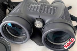 Bushnell 10x42 H20 Binoculars, never been used see, If you are a hunter, sailor, boat enthusiast, kayaker or even a snow bunny and need a good accessory then the Bushnell H20 10x42 Roof binoculars are exactly what you are looking for! These binoculars are made to be rough and tough and able to handle a downpour or even a quick dip in the water as they have been enhanced with a soft-texture grip for better handling inchallenging conditions as well as being water- and fogproof.
Magnification x Objective lens: 10x 42
Size Class: Standard
Focus System: Centre
Prism System: Roof
Prism Glass: BaK-4
Close Focus: 3.6 mm
Lens Coating: Multi-coated
Field of view (@ 1000 m): 102 m
Exit Pupil (mm): 4.2
Eye Relief: 17 mm
Eye cups: Twist-up
Water- and fogproof
Weight: 708.5 grams
